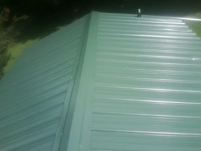 New green metal panels meeting at the ridge of a roof — Flat Roof Repair work by our crew in Randolph
